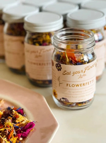Multiple jars of Eat Your Flowers organic edible confetti sitting on a table next to a pink bowl of confetti
