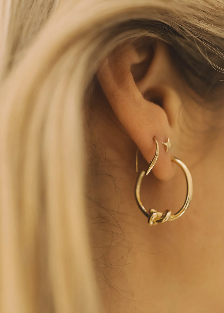 Close-up of a gold hoop earring worn by a person with blonde hair.