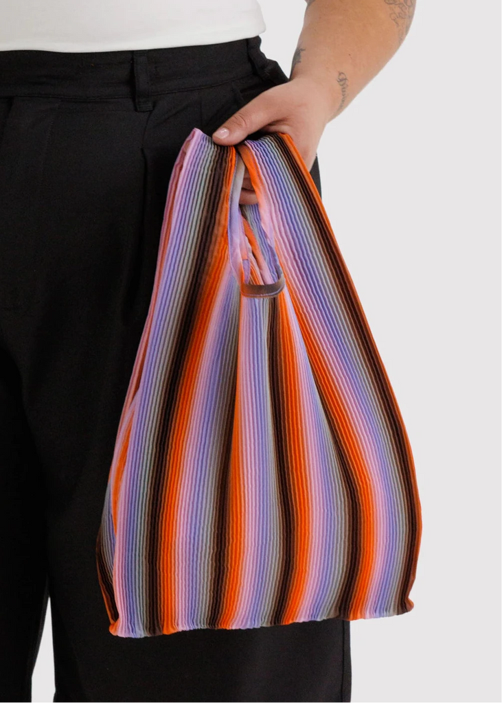 Person holding a colorful striped bag against a white background