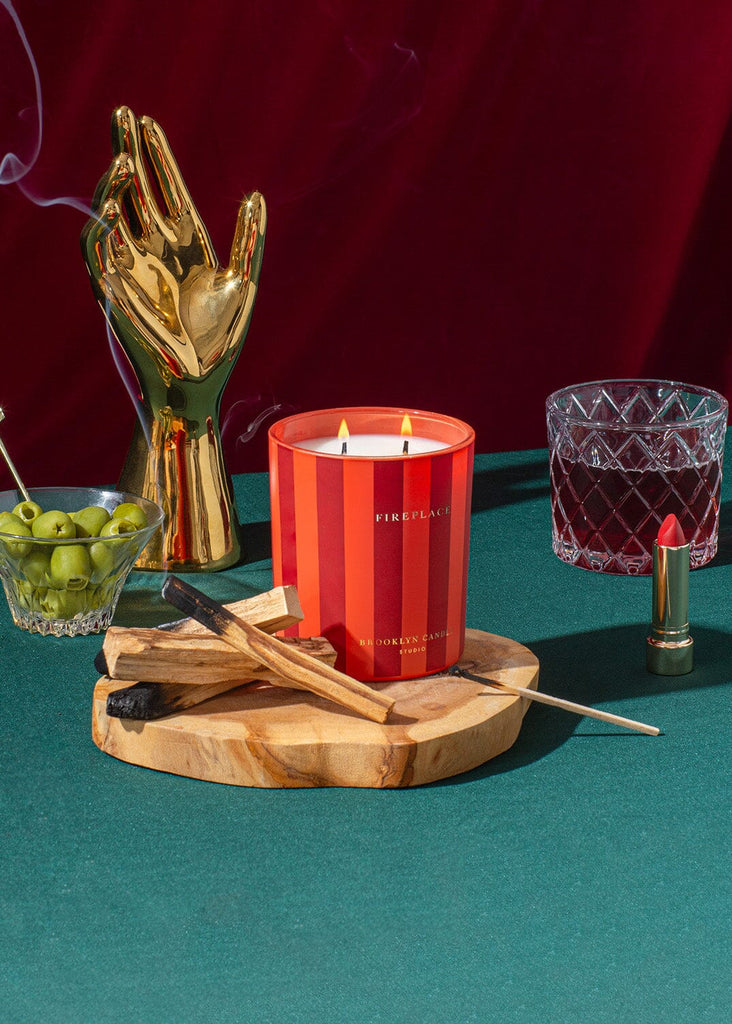 Red candle with decorative items on a wooden board against a red background