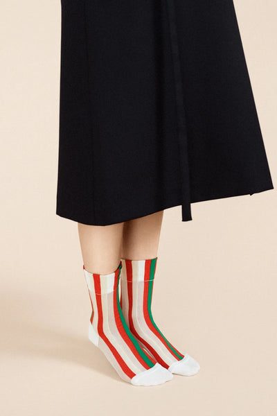 a person wearing a black skirt with a pair of Hansel from Basel's festival striped socks in red, white, and green.