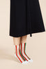 a person wearing a black skirt with a pair of Hansel from Basel's festival striped socks in red, white, and green.