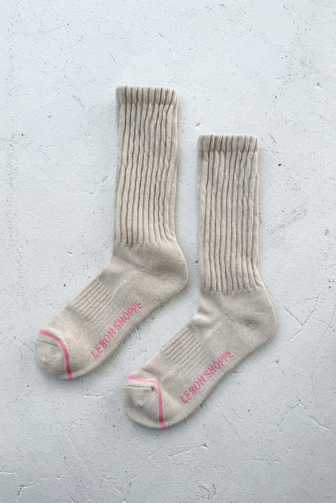 Pair of beige socks with pink accents on a light gray background