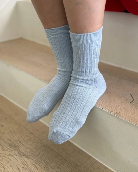 Le Bon Shoppe Her Glitter Socks in the color Morning Mist worn by a person sitting on a wooden step.