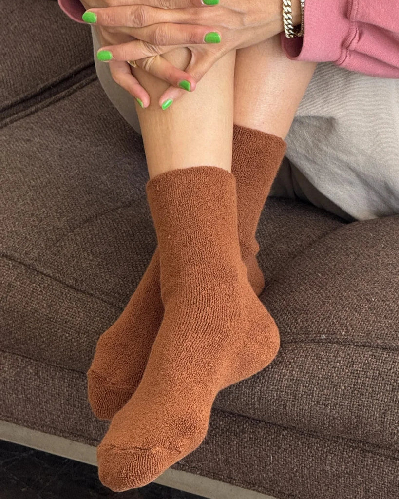 Person wearing a pair of Sepia cloud socks from Le Bon Shoppe sitting on a brown couch.