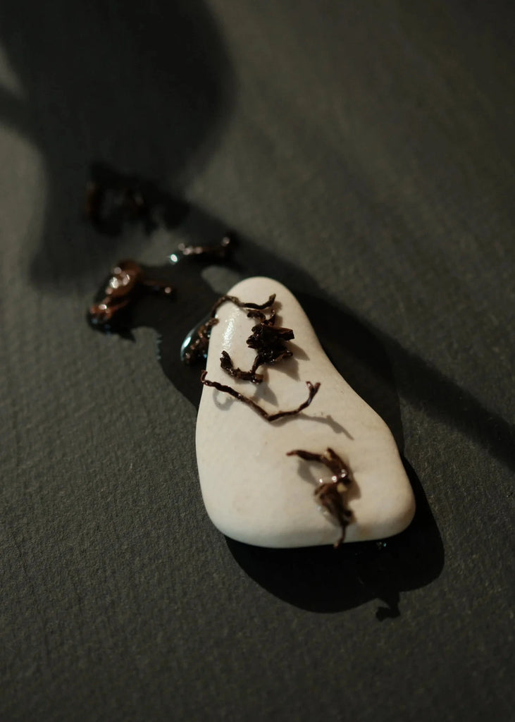 White stone with copper-hued black tea leaves on a dark surface