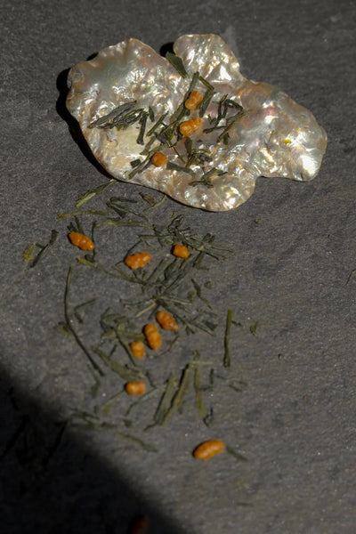 loose genmaicha tea is spilled on a slate tile 