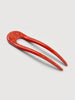 a poppy red French hair pin by machete sitting on a white background.