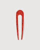 a poppy red French hair pin by machete sitting on a white background.