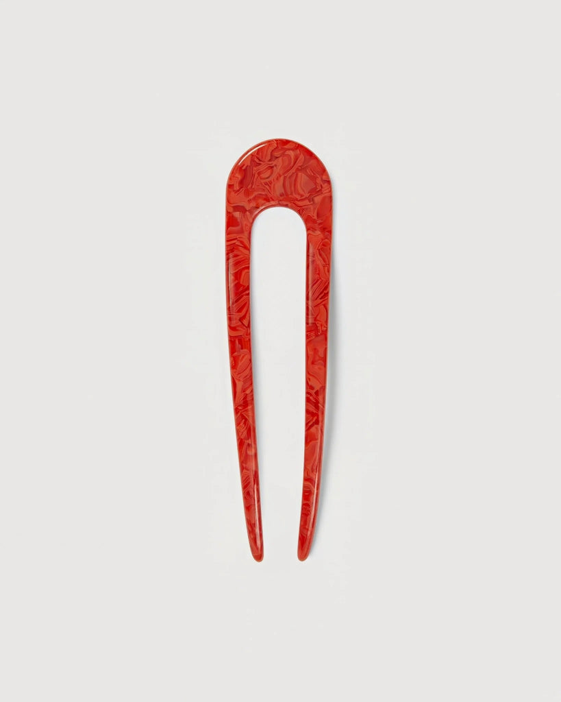 a poppy red French hair pin by machete sitting on a white background.