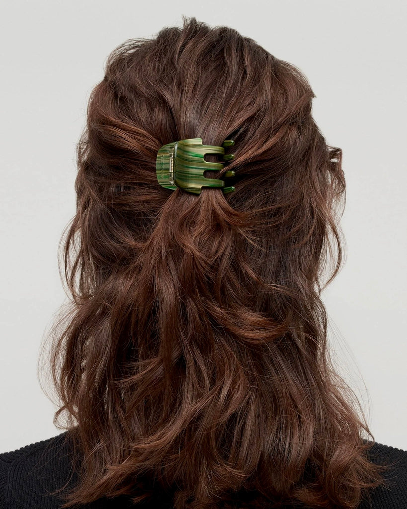 a woman with a black shirt and brown hair is wearing a mini claw hair clip by machete.