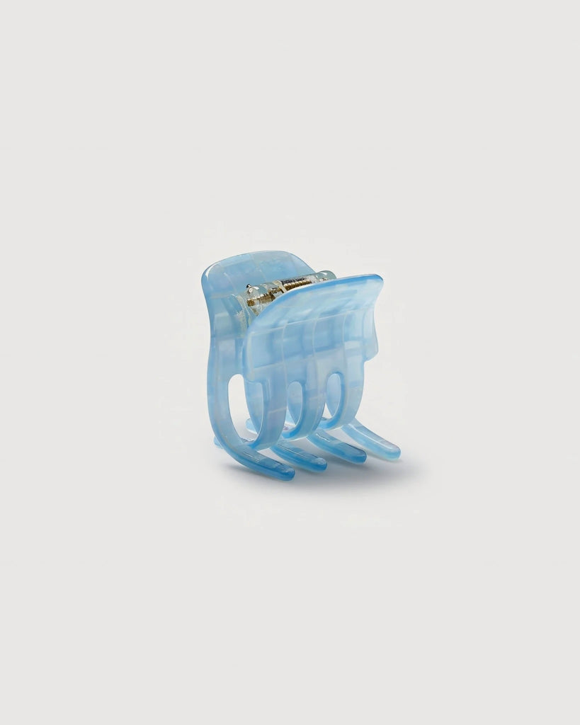 a blue shell mini claw hair clip by machete sits on a white background.