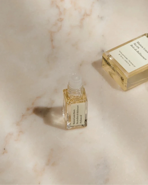 a small open sample bottle of maison Louis Marie's bois de balincourt sits on a tan marble background.