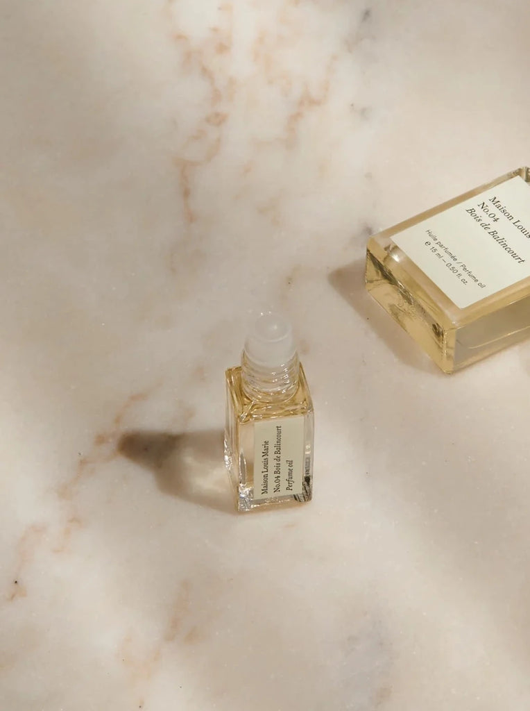 a small open sample bottle of maison Louis Marie's bois de balincourt sits on a tan marble background.