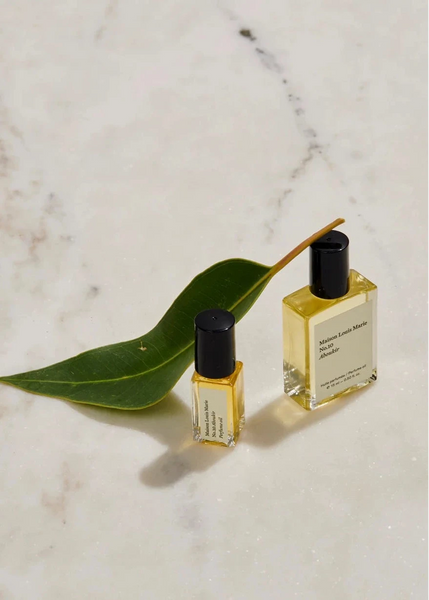 a bottle of maison louie Marie's no. 10 aboukir perfume oil sits on a marble background with a leaf resting on the ground.