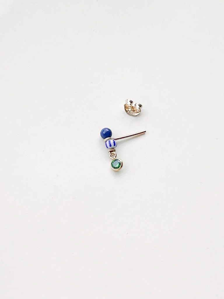 earring with a blue bead, a striped bead, and a green gem sitting beside an earring back against a white background