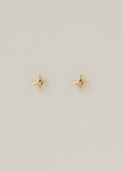 Gold star-shaped earrings on a light gray background