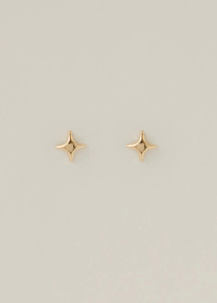 Gold star-shaped earrings on a light gray background