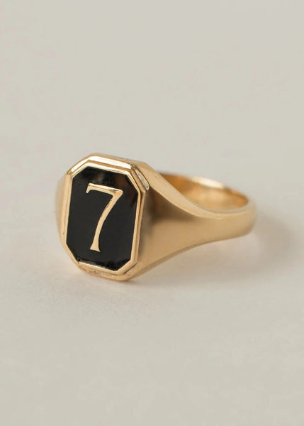 Gold ring with a black number '7' on a light gray background