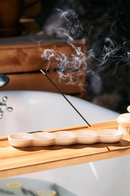 incense burning in an incense holder on top of a bath tray in the sunshine