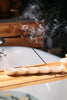 incense burning in an incense holder on top of a bath tray in the sunshine