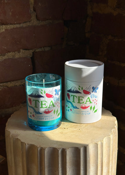 Tea candle in a blue glass container and white package against a brick wall background