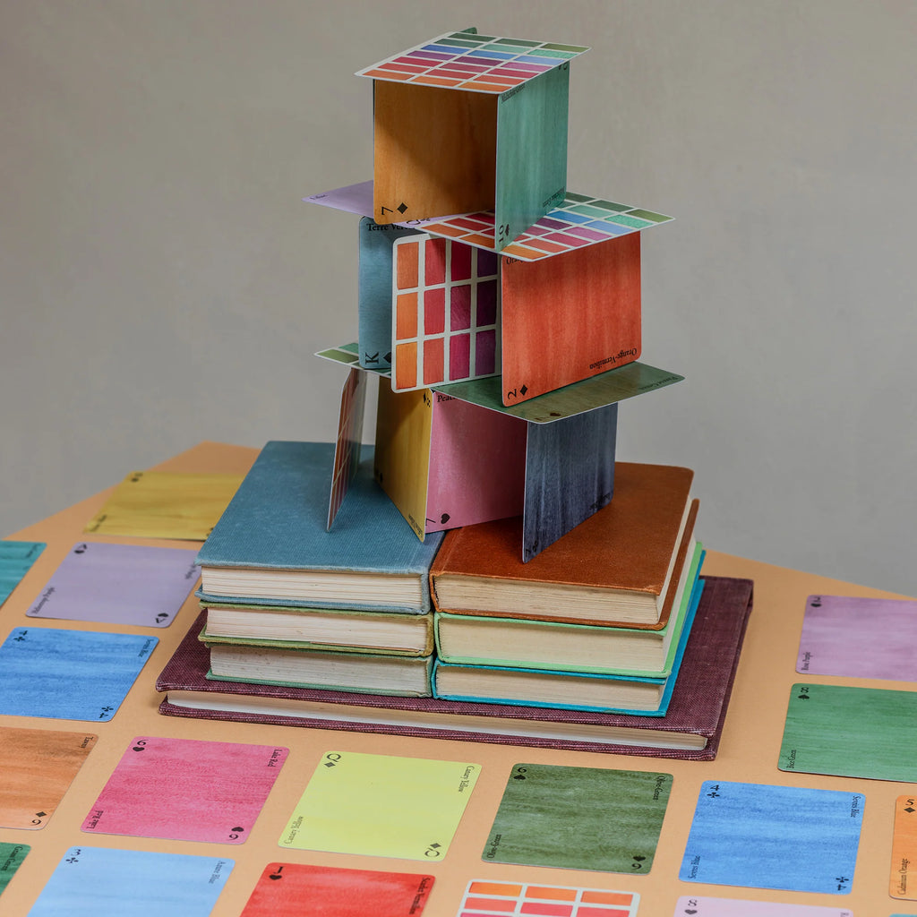 a pack of colorful playing cards arranged in a playful pyramid on a table.