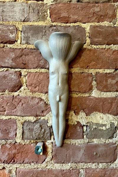 Front view of a raw stoneware wall vase in the shape of a male presenting body with flower petals for a head, by Rose Grown Ceramics.