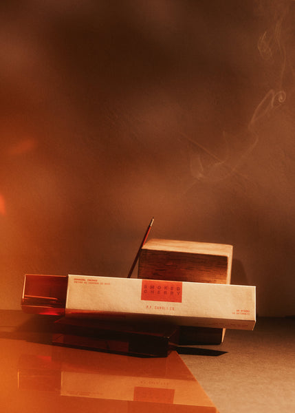 smoked cherry Incense sticks and box with smoke on a dark background