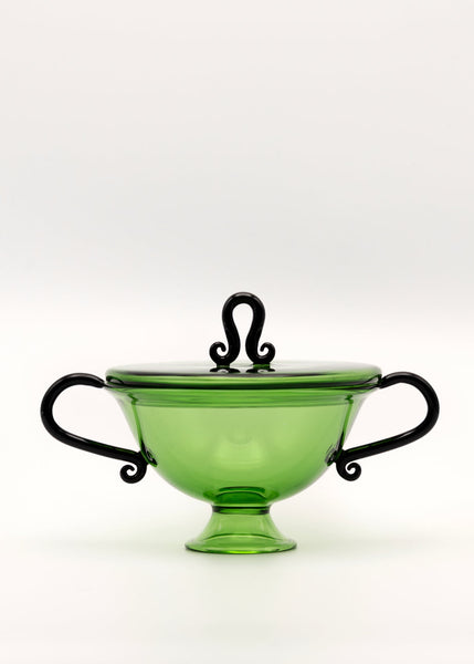 Green glass candy dish with black handles and lid finial on a white background