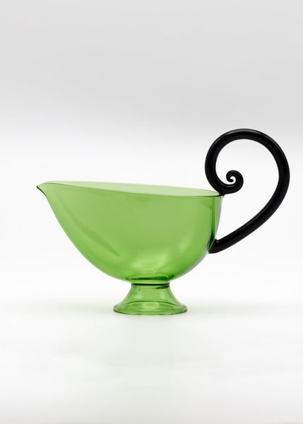 Green glass saucier with a black handle on a white background