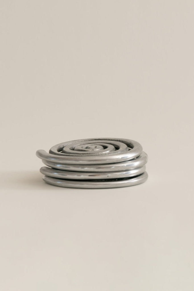 four silver spiral metal coasters stacked