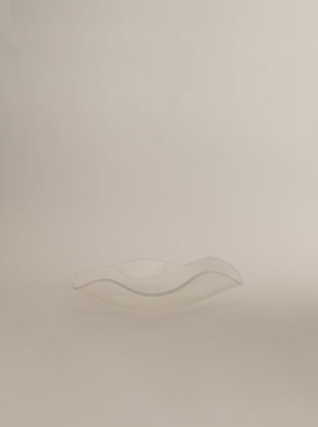 Sophie Lou Jacobsen's opal clear colored glass plate with a petal shaped wavy rim sits on a white background