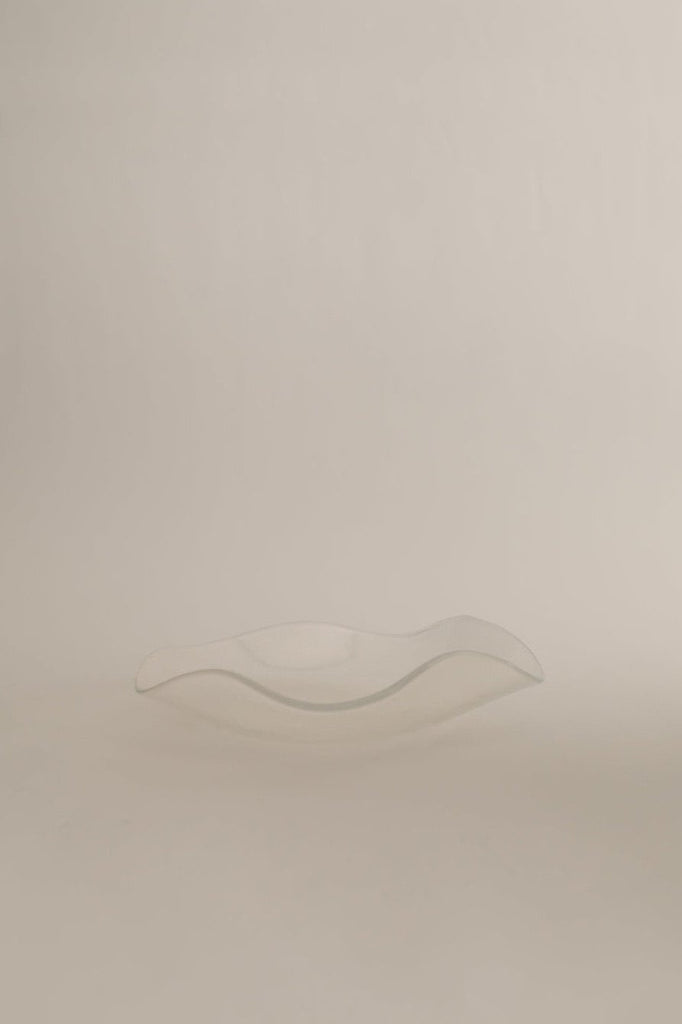 Sophie Lou Jacobsen's opal clear colored glass plate with a petal shaped wavy rim sits on a white background