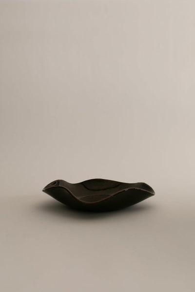 Sophie Lou Jacobsen's pecan brown colored glass plate with a petal shaped wavy rim sits on a white background