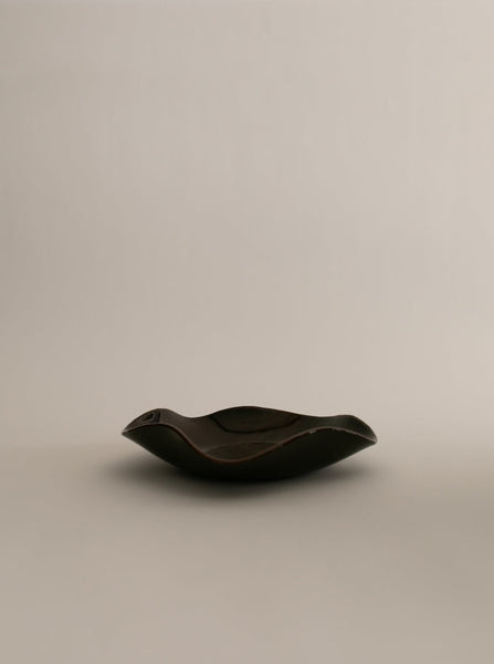 Sophie Lou Jacobsen's pecan brown colored glass plate with a petal shaped wavy rim sits on a white background