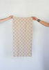 tan colored checkerboard Turkish hand towel being held up by two people