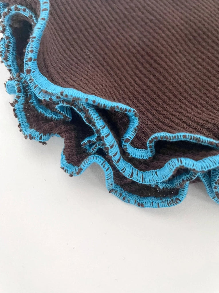 close up photo of brown waffle knit cotton washcloths with blue trim in a stack 