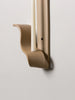 detail of a tan ceramic wall sconce resembling a ribbon made by sin ceramics holds a lit beeswax taper on a white wall