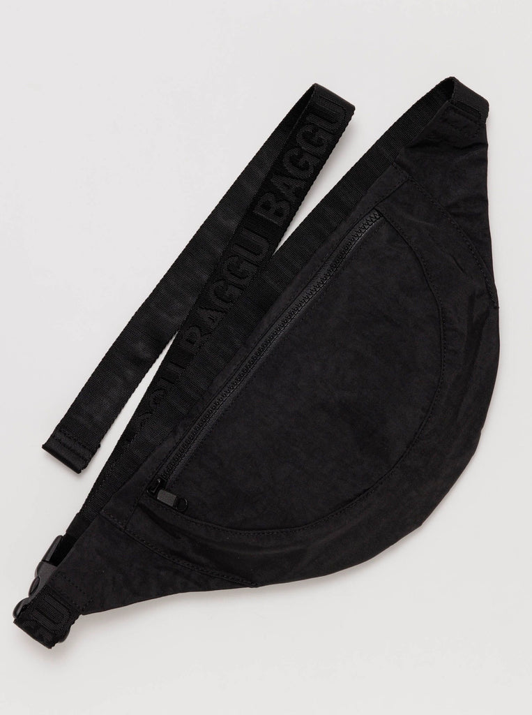 A black crescent shaped nylon fanny pack with black front zipper and a black strap made by baggu against a white background