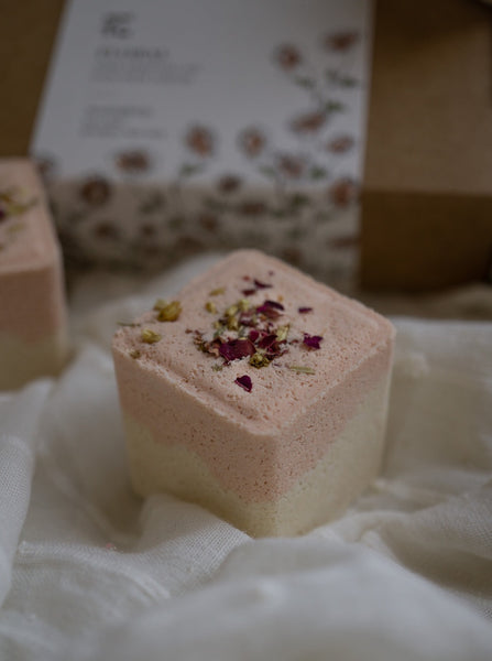 An even keel floral bath fizzy or shower steamer infused with signature Lavender blends of 100% pure essential oils and dried botanicals sitting on white fabric 