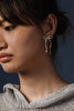 Woman wearing silver bow earrings by Kara Yoo against a dark background 