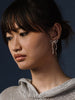 Woman wearing silver bow earrings by Kara Yoo against a dark background 