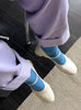 A person wearing electric blue le bon shoppe her socks and purple pants with white shoes
