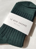 A dark green pair of ribbed her socks with a white le bon shoppe label against a white background 