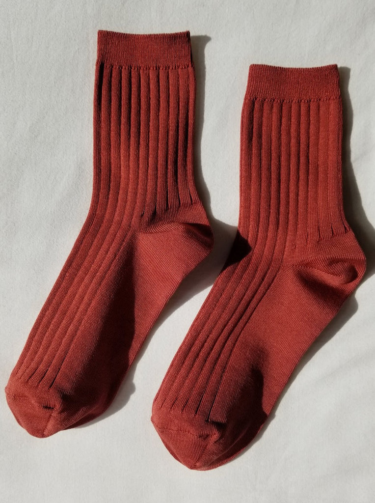A pair of terracotta red ribbed le bon shoppe her socks against a white background 