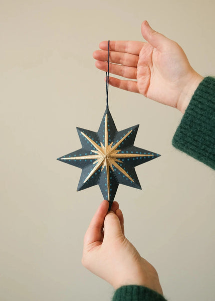 Hand holding a star-shaped decorative ornament against a plain background