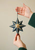 Hand holding a star-shaped decorative ornament against a plain background